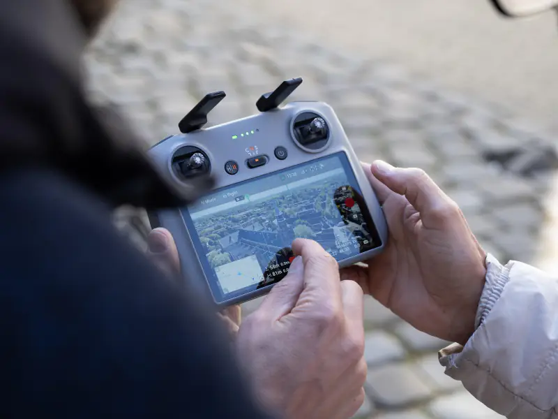 DJI-controller in de hand met live beeld van de daken van de stad