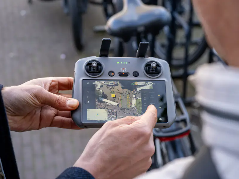 DJI-controller met live beeld van een marktplein, recht van boven gefilmd met de drone