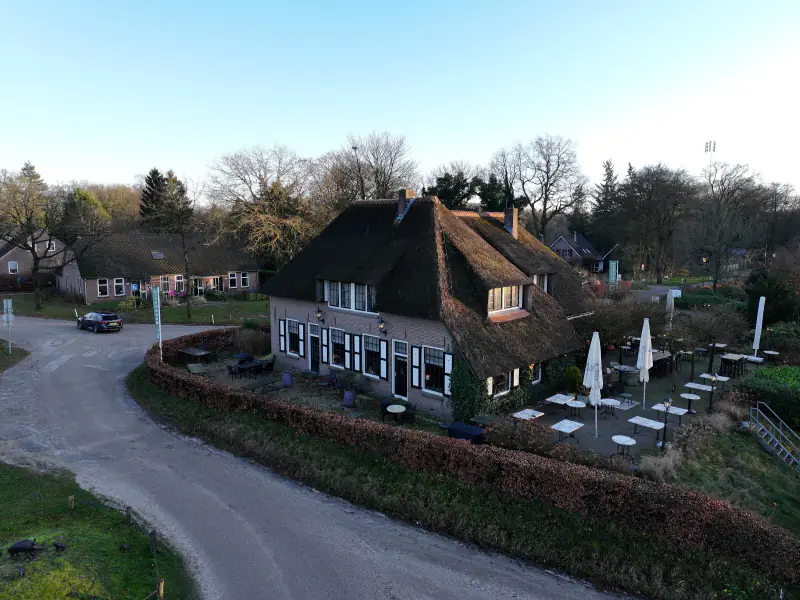 Rietgedekte herberg in Hoog Soeren in het late licht, vanuit de drone