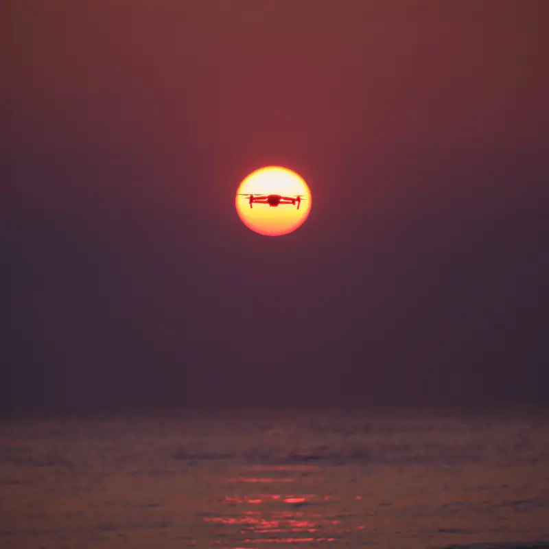 Silhouet van een drone voor de ondergaande zon boven zee