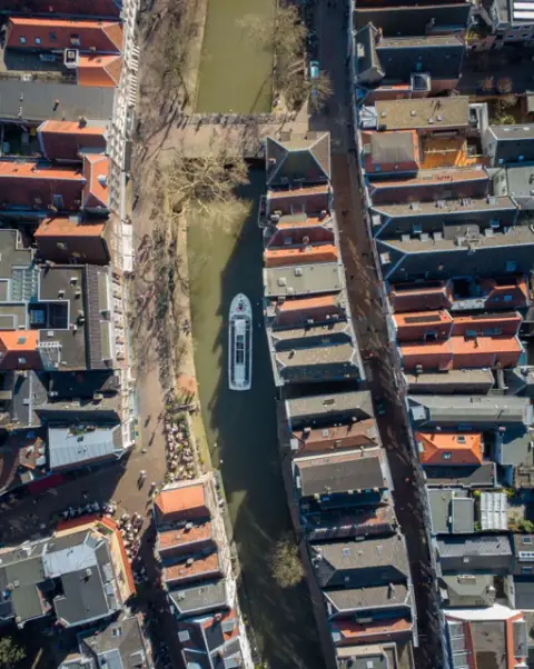 Rondvaartboot in een gracht tussen de daken, recht van boven