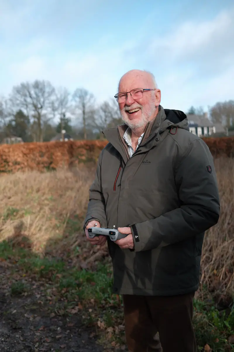 Opa lacht met de controller in zijn handen, op de heide bij Hoog Soeren