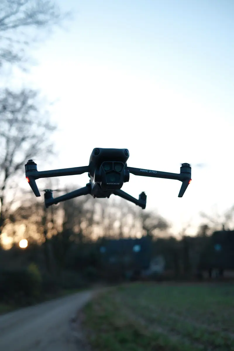 De drone hangt laag in de lucht boven het pad, bij schemering