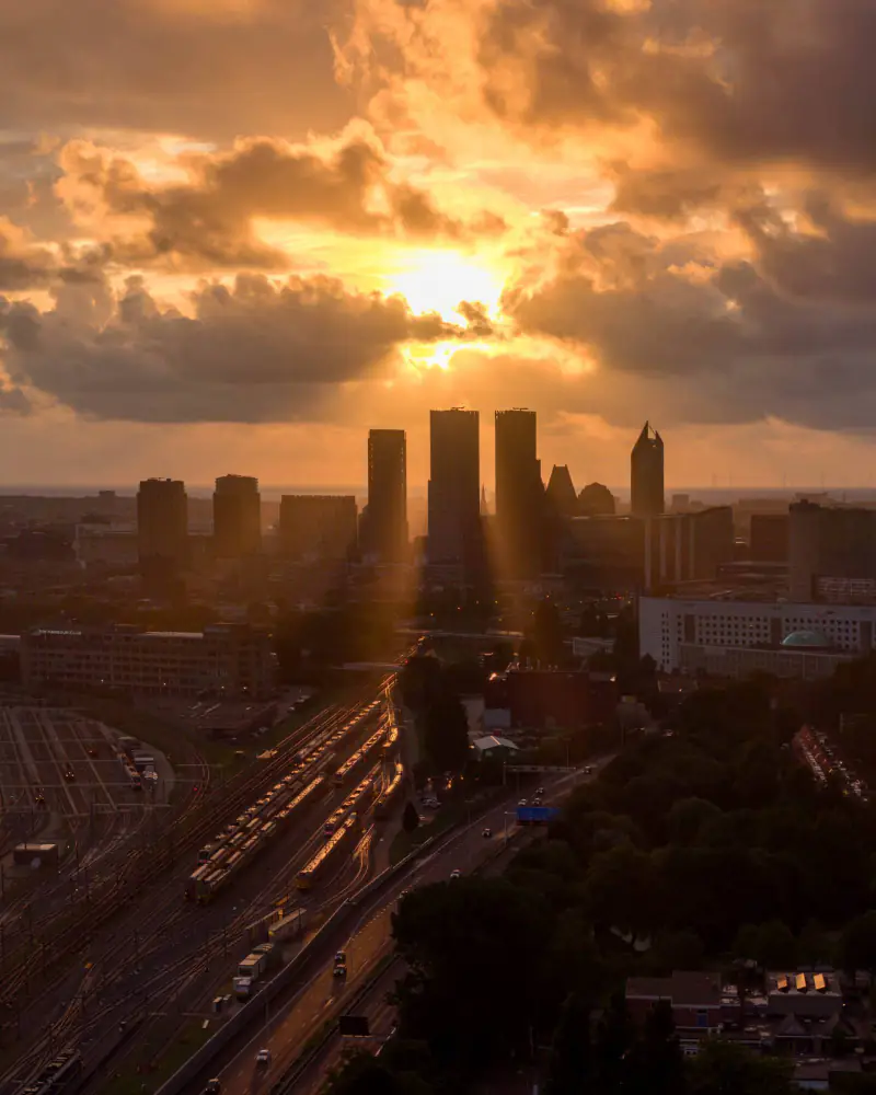 De skyline van Den Haag bij zonsondergang, gezien vanuit Voorburg, met het spoor op de voorgrond