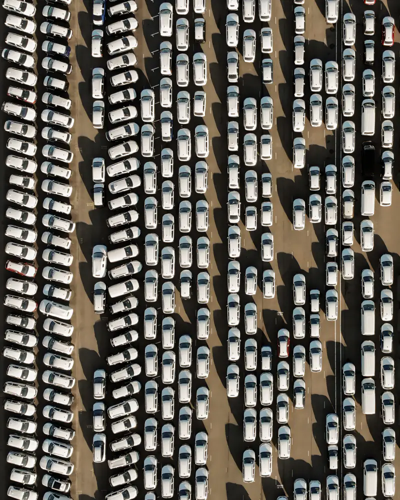 Rijen witte auto's op een parkeerterrein, recht van boven