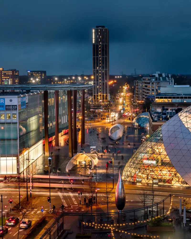 Stadscentrum met woontoren en lichtsporen in de avond, vanuit de lucht