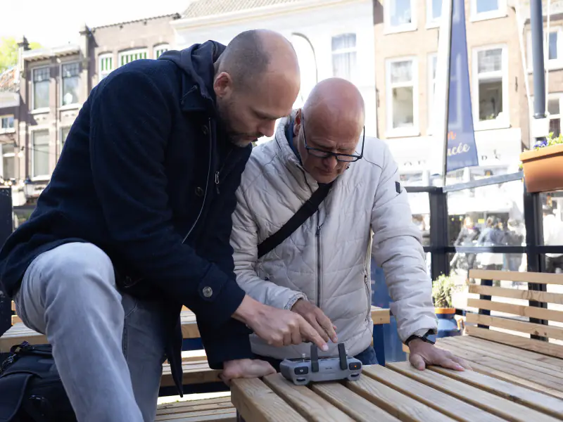 Uitleg van de controller aan een deelnemer tijdens een workshop dronevliegen in de stad